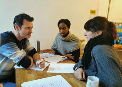 two women on one side of the table look at a man on the other side