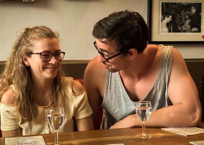 a woman sits in a booth and a man sits next to her looking at her and talking