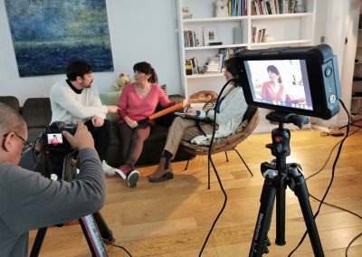 3 actors on set in front of the director who is setting up the camera